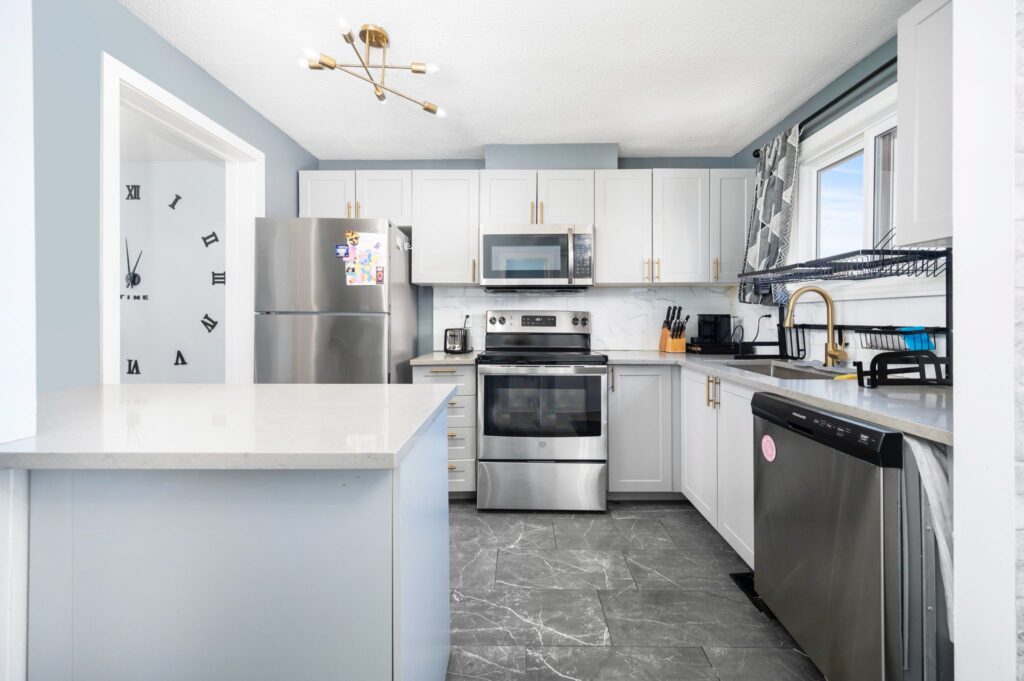 Option 1 (Direct & Comprehensive): Modern kitchen remodel by Mo Reno in Ottawa with white cabinets, stainless steel appliances, and dark countertops.