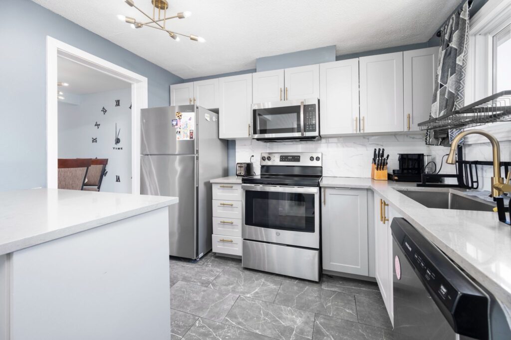 Transitional kitchen renovation in Ottawa by Mo Reno with warm wood cabinets, light granite countertops, and a large central island.