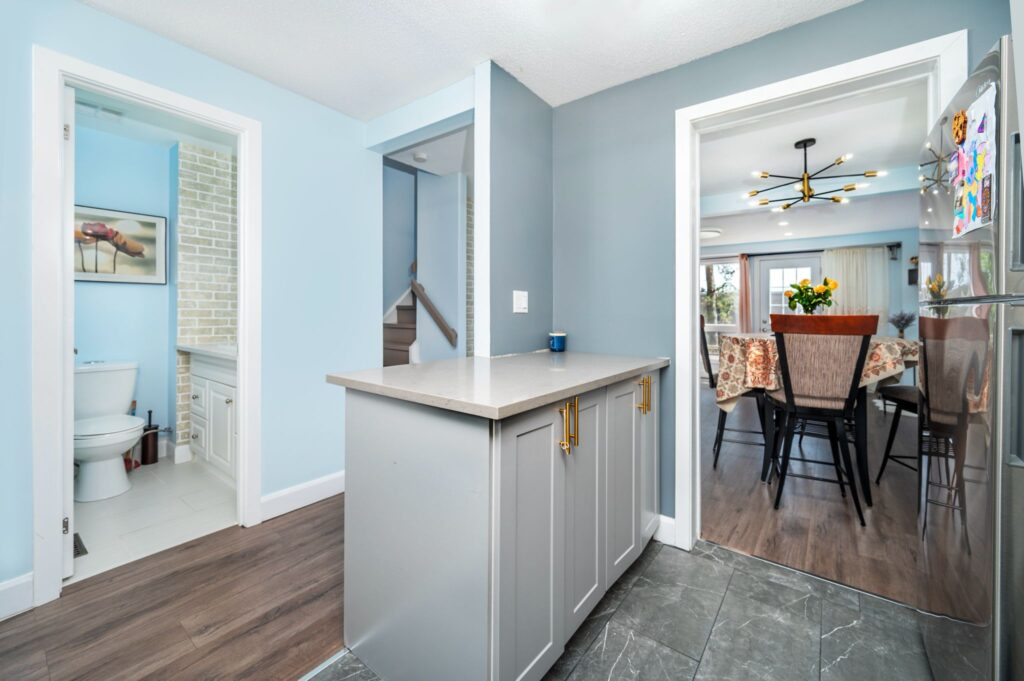 Modern kitchen remodel by Mo Reno in Ottawa with white shaker cabinets, dark countertops, and stainless steel appliances.