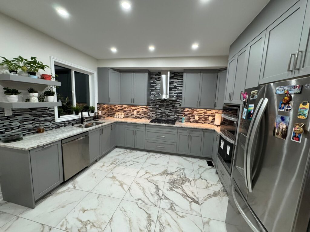 Modern grey kitchen renovation with quartz countertops, patterned tile backsplash, stainless steel appliances, and large-format marble porcelain flooring.