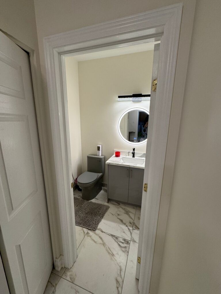 Full bathroom renovation with corner glass shower, soaking tub, grey vanity with wavy LED light, and floor-to-wall marble porcelain tiles.