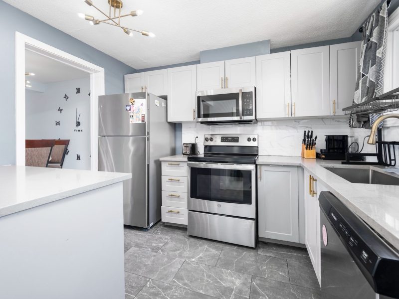 Transitional kitchen renovation in Ottawa by Mo Reno with warm wood cabinets, light granite countertops, and a large central island.